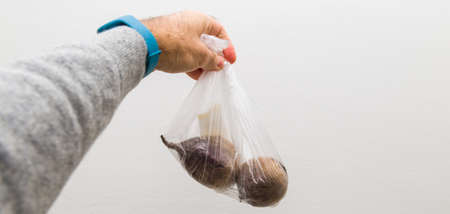man holding plastic transparent package with two beets bio organic against white isolated backgroundの写真素材