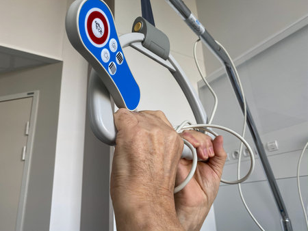 Senior male hand holding patient lifting pole with grab handle and signal buttons for nurse call,...