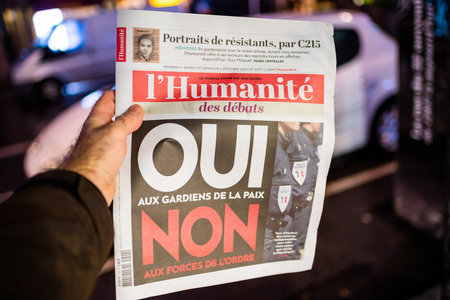 Strasbourg, France - Dec 4, 2020: Man holding lHumanite newspaper at French press kiosk announcing the debate between yes or no for guardians for peace instead of police forcesのeditorial素材