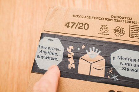 Paris, France - Dec 12, 2020: POV male hand pointing to Low Price Anytime, Anywhere advertising on the package of Amazon Prime winter Christmas holiday scotch bandのeditorial素材