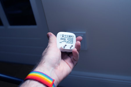 Paris, France - Dec 8, 2020: Male hand holding night light Ledvance Lunetta Wave VT next to power outlet - ready to be pluggedのeditorial素材