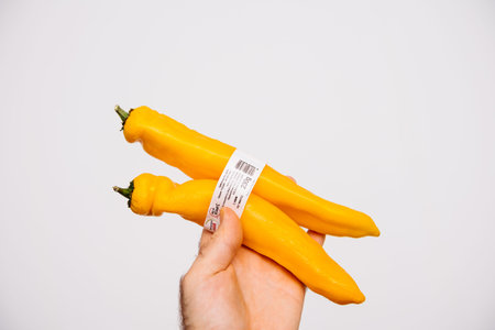 Paris, France - Dec c30, 2020: POV male hand showing demonstrating a bunch of sweet yellow peppers...
