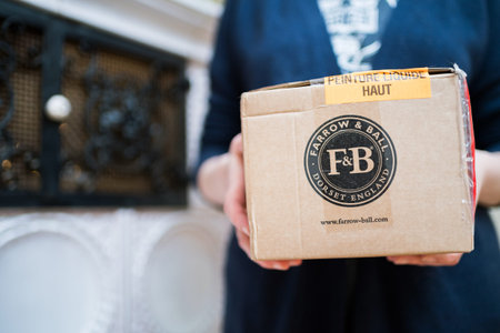 Paris, France - Dec 13, 2020: Woman holding parcel package with Farrow and Ball Dorset England luxury paint - sticker - liquid paint keep rightのeditorial素材