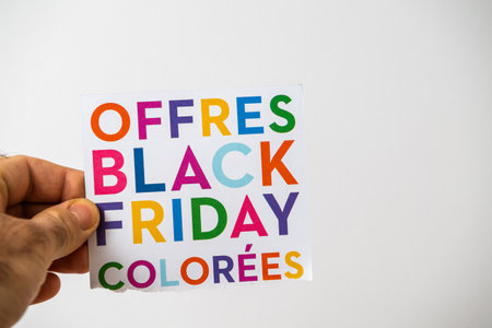 POV male hand holding flyer with Black Friday offers colorful letters during the annual saleの写真素材