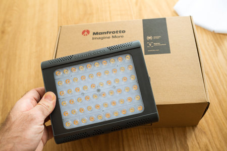 Paris, France - Dec 8 2020: POV male hand unboxing unpacking new Manfrotto LED Light Lykos 2.0, 2 in 1 water-resistant with Bluetooth package in backgroundのeditorial素材