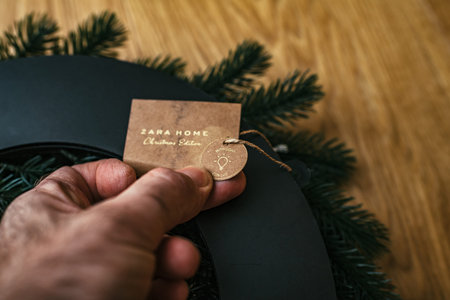 Paris, France - Dec 13, 2020: POV male hand holding Zara home Christmas Edition price tag with light...
