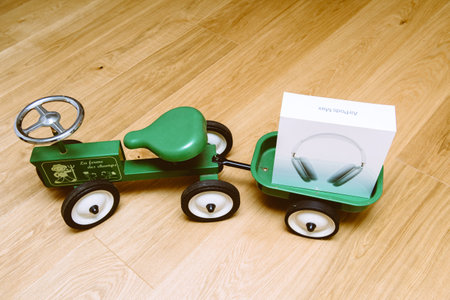 Paris, France - Jan 7, 2020: Overhead view of Kid child green tractor toy with Apple Computers AirPods Max over-ear headphones in the carriage trunkのeditorial素材