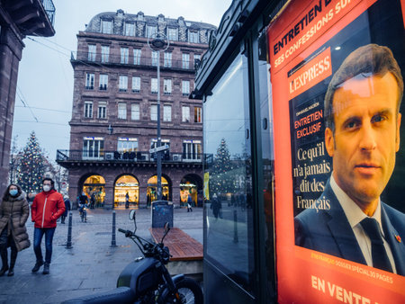Strasbourg, France - Jan 7, 2021: People with anti-Covid-19 masks on French city Street with portrait of French President Emmanuel Macron on the cover of LExpress interview advertising at press kioskのeditorial素材