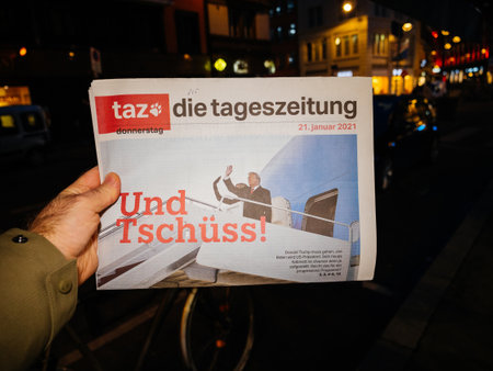 Paris, France - Jan 21, 2021: POV man buying Taz die tageszeitung German newspaper headline words Und Tschuss translated as good bye featuring Donald and Melania Trump leaving the presidencyのeditorial素材