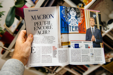 Paris, France - Feb 21, 2019: POV male hand holding French magazine with portrait of emmanuel Macron French presidentのeditorial素材