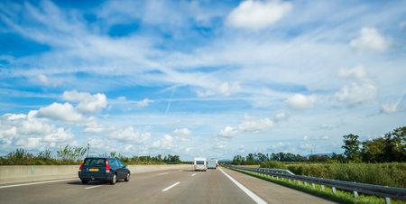 Germany - Sep 22, 2018: Wide angle view of large German autobahn with sunny day with scattered cumulus cloud cand VOLVO V70 wagon car next to RV vans driving fastのeditorial素材