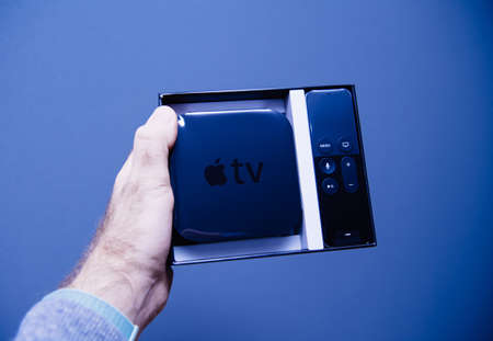 Paris, France - Nov 14, 2018: Point of view male hand holding showing unboxed Apple TV the digital media player and microconsole developed and sold by Apple Computers Incのeditorial素材