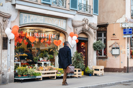 Strasbourg, France - Feb 14, 2019: Man walking near Fleurs Broglie La Fleuristerie florist store shop showcase decorated with multiple hearts during Saint Valentine dayのeditorial素材