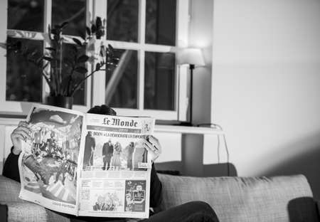 PARIS, FRANCE - JAN 21, 2021: Woman reading Le Monde newspaper featuring breaking news and headlines with Joe Biden inauguration as the 46th President of the United States and Kamalla Harrisのeditorial素材