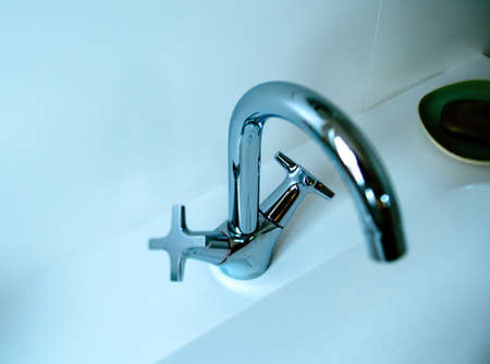 Close-up view from above of water tap in blue-color tones tilt-shift photoの写真素材