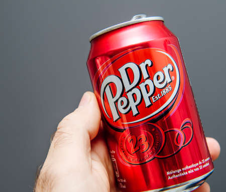 Paris, France - May 3, 2020: POV male hand holding aluminum can of Dr Pepper manufactured by Dr Pepper Snapple Group soft sweet drinks - isolated against gray backgroundのeditorial素材