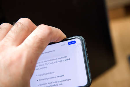 PAris, France - Jan 14, 2021: Male hand holding new Apple Computers iphone 12 Pro cracked display - Apple Care Plus information on display with Buy Now button activatedのeditorial素材