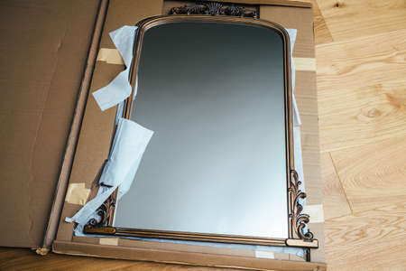Unboxing inspecting new vintage wooden luxury framed mirror delivered without any flaws in the cardboard package - security safety during transportation of fragile objectsの写真素材