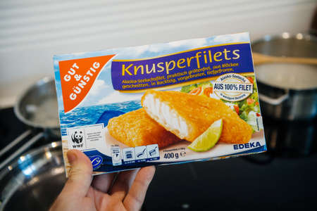 Paris, France - FEb 13, 2021: POV male hand holding new pack with frozen fish from Edeka Gut und Gunstig traditional knusperfilets - kitchen backgroundのeditorial素材