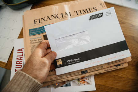 Paris, France - FEb 13, 2021: POV male hand holding letter correspondence from Financial Times newspaper with Welcome the world of business inscription - newspaper on backgroundのeditorial素材