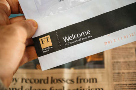 Paris, France - FEb 13, 2021: POV male hand holding letter correspondence from Financial Times newspaper with Welcome the the world of business inscriptionのeditorial素材
