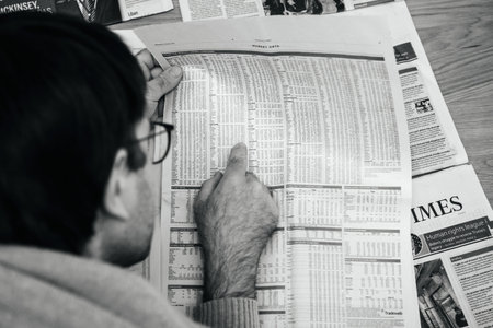 Paris, France - FEb 13, 2021: POV male hand reading FT weekend Financial Times looking carefully on...