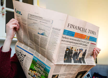 Paris, France - Mar 2, 2021: Business woman reading Financial Times newspaper with headline Former French President Nicolas Sarkozy sentenced to 3 years jail in historic rulingのeditorial素材