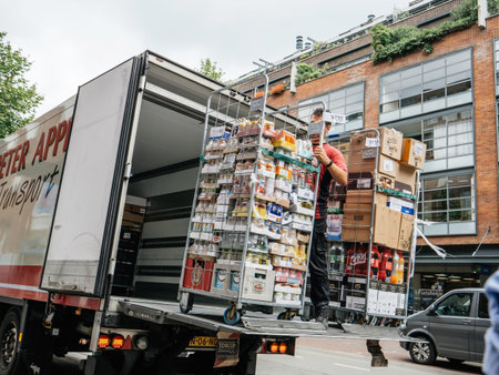Haarlem, Netherlands - Jul 21, 2018: Dutch street scene with large truck unloading multiple drinks on the platform to be delivered for supermarkt bar or restaurant - male holding carriageのeditorial素材