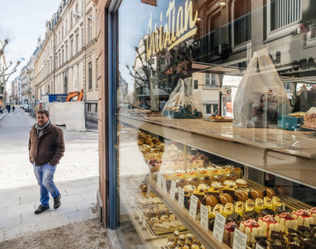 Strasbourg, France - Feb 23, 2019: Adult male walking on the street with multiple pastries sweets in the showcase glass vitrine of Christian patisserieのeditorial素材