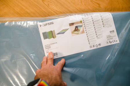 Paris, France - Mar 10, 2021: POV Male hands showing the package of new Plufsig folding gym mat manufactured by IKEA Swedenのeditorial素材