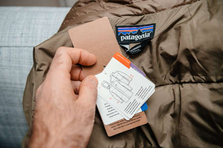 Lyon, France - Feb 16, 2021: POV male hand reading tag of new parka duvet manufactured by Patagonia model Mens tres 3-in-1 parka regular fit luxury winter clothes - all components descripedのeditorial素材