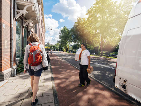 Woman walks on Dutch street near delivery man with parcelsのeditorial素材