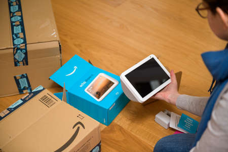 Overhead view of young woman unboxing Amazon Alexa smart speakerのeditorial素材