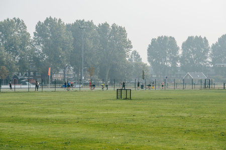 Telephoto view of large sport area secured by a fence with children and adult playing doing workouts