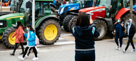 WOman takes photos of tractorsa at farmer protest