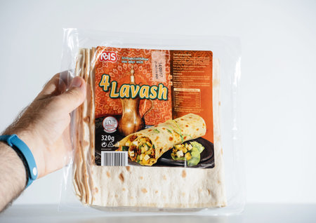 Male hand holding package with 4 lavash bread in plastic package