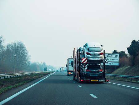 Rear view of long cargo truck carrying on the highway multiple Opel carのeditorial素材