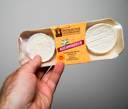 POV male hand holding package of delicious Rocamadour cheese