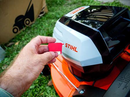 Pov male hand holding new red activation Key for Stihl RMA lawn mowerのeditorial素材