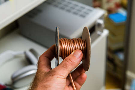 holding audio connection wire cable with audio hi-fi system in backgroundの写真素材