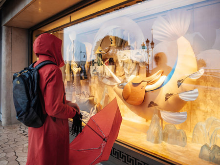 Rear view of woman with red umbrella looking at the Valentino flagship store in center of Monaco