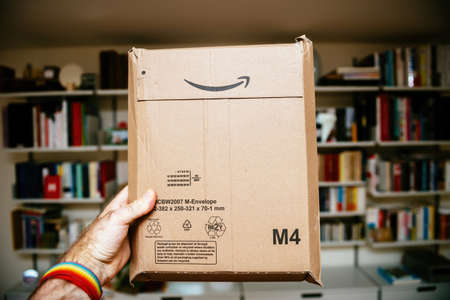 POV male hand holding new parcel delivered by Amazon Prime with rear view envelope codesのeditorial素材