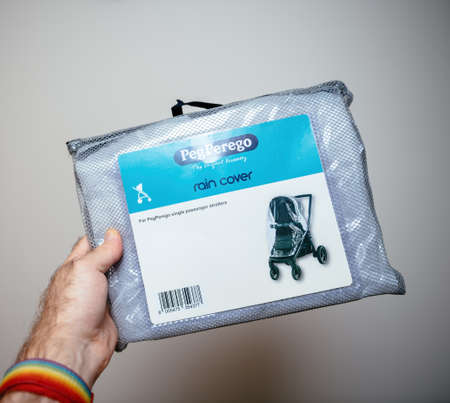POV male hand holding new Peg Perego rain cover for single passengerのeditorial素材