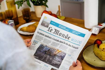 Woman reading in the kitchen early in the morning Le Monde newspaperのeditorial素材