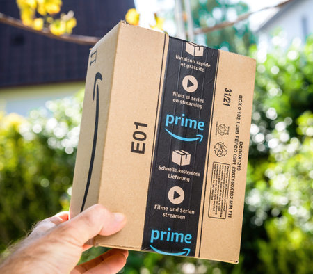 POV male hand holding new Amazon Prime cardboard parcel