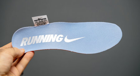 Male hand holding new running Nike shoe sole in blue color