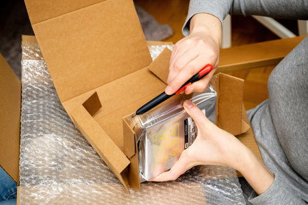 Side view of woman hand unboxing unpacking Western Digital HDD hard disk drive in plastic bubble wrapのeditorial素材