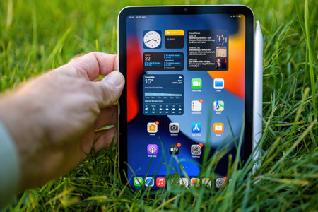 Male hand holding latest Apple Computers iPad Mini stylish compact design with Apple Pencil charging
