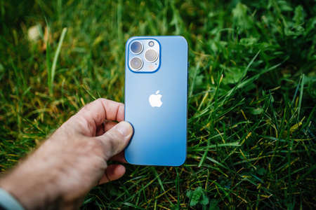 Apple Computers iPhone 13 pro with all three rear cameras and lidar sensor in green garden grass background environmentally friendlyのeditorial素材