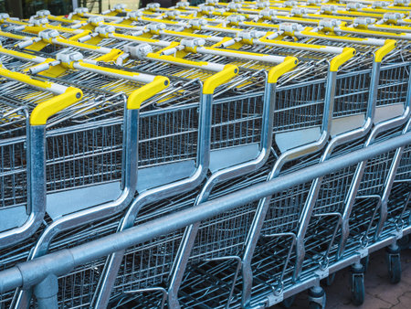 multiple metallic supermarket shopping carts in large parking